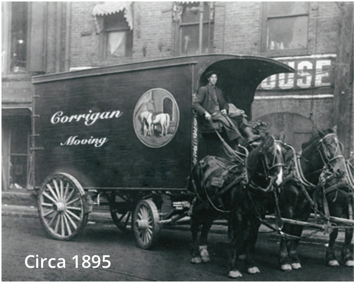 A black and white photo of a horse-drawn moving wagon.
